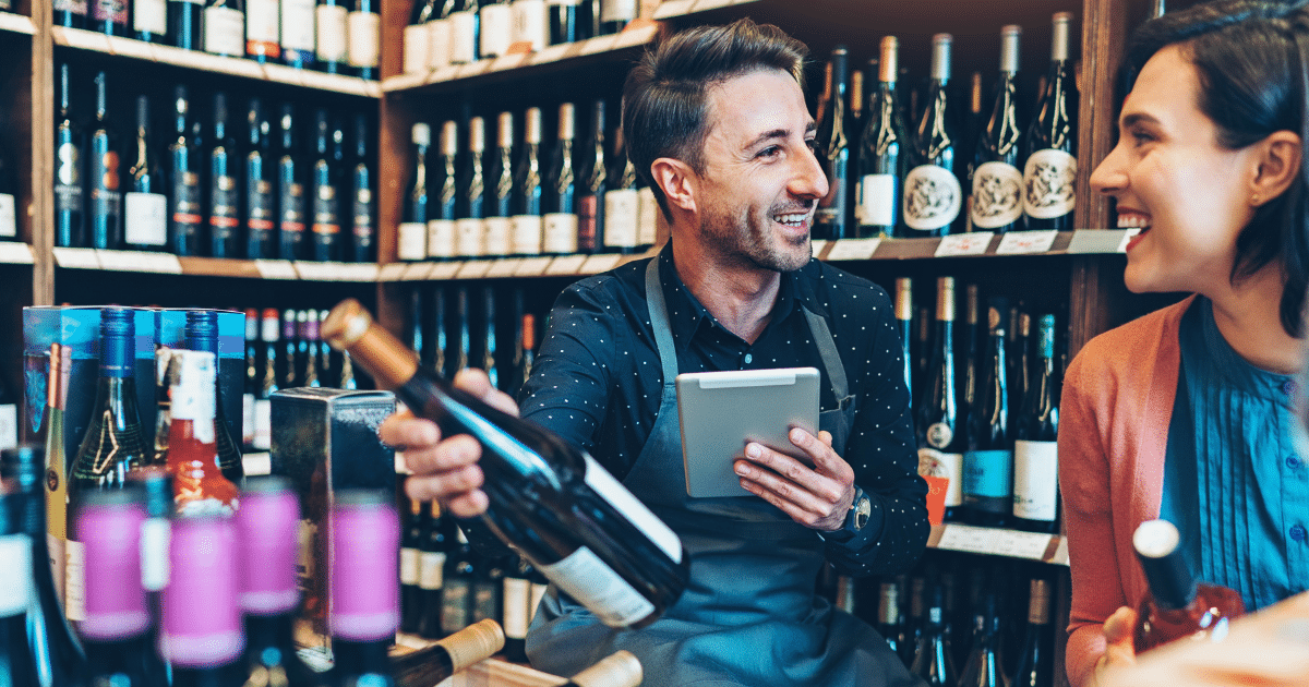 Liquor store owner assisting a customer with business loans, showcasing inventory and customer service in a vibrant store.