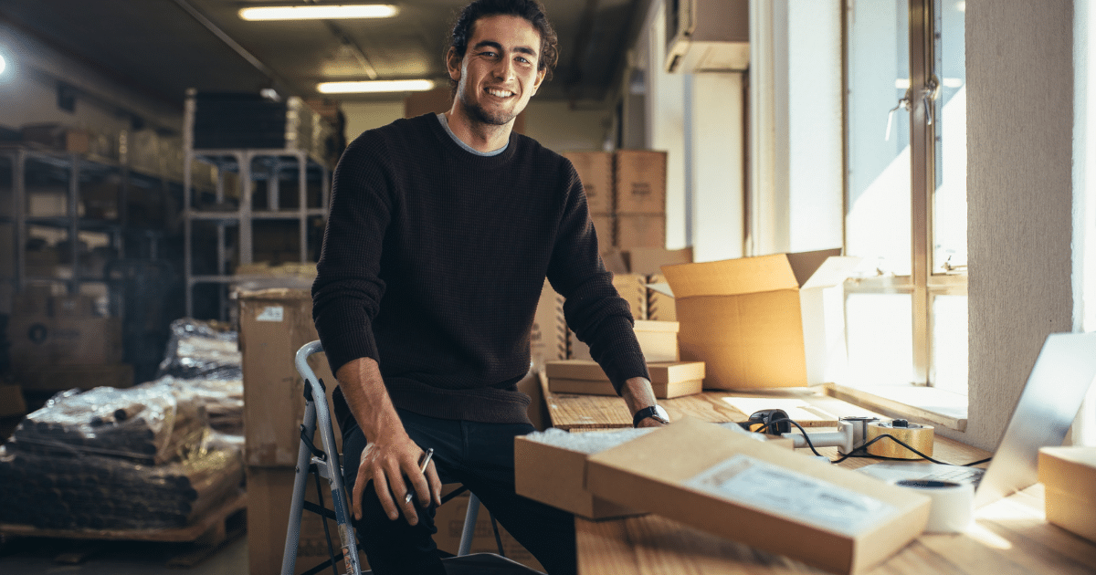 Smiling young man in a warehouse, showcasing equipment leasing and finance solutions for construction businesses.