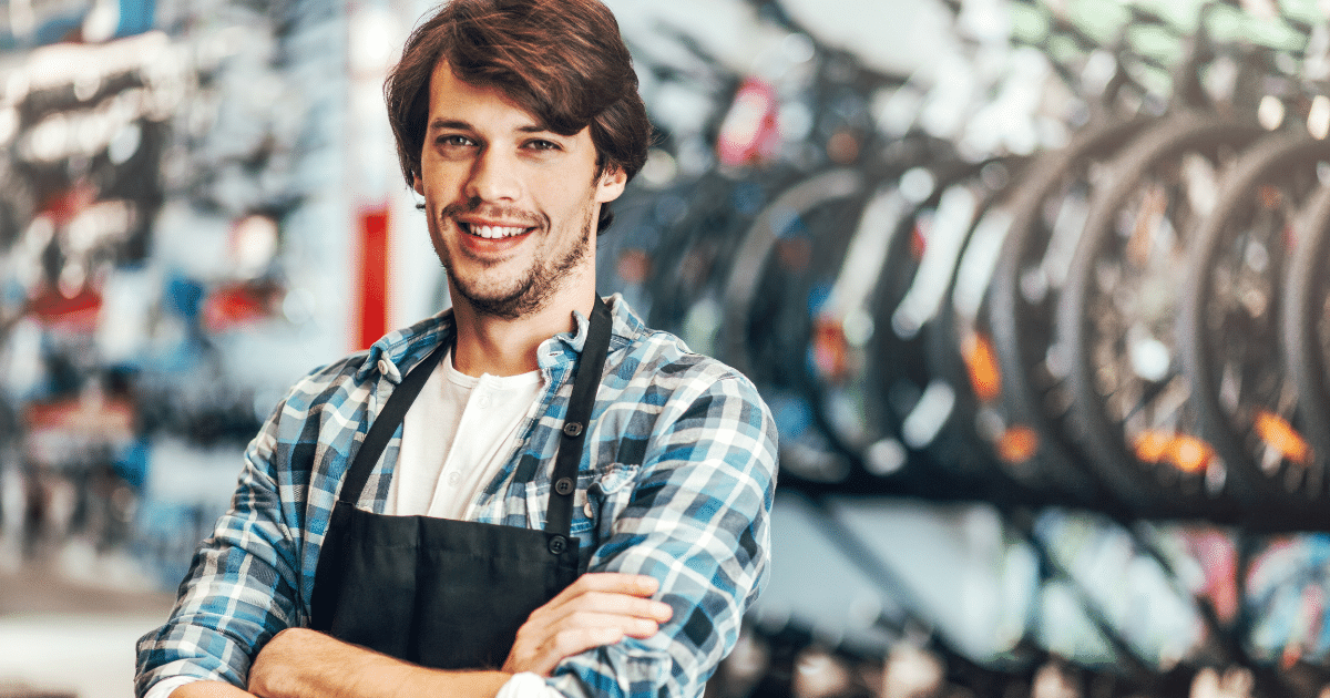 Smiling young man in a bike shop, representing effective marketing strategies for small businesses on a budget.