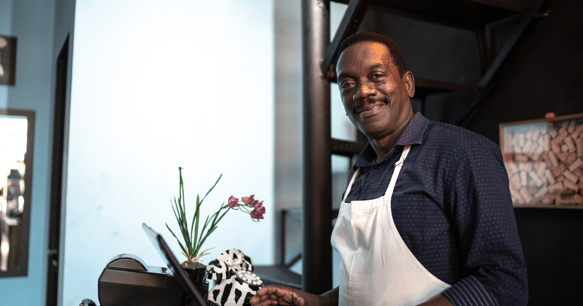 Smiling small business owner in a cafe, showcasing expert funding solutions for small business success.