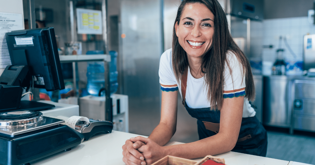 Smiling business owner at a counter, representing innovative equipment leasing and finance for business growth.