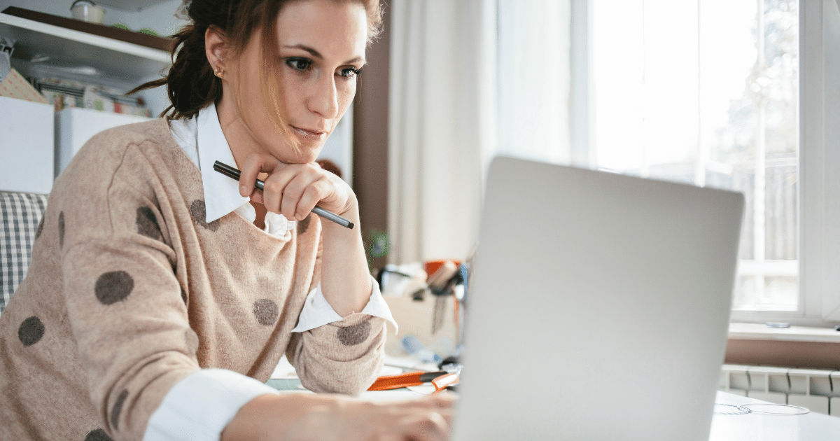 Woman working on a laptop, focused on achieving professional greatness and sustainable success strategies.