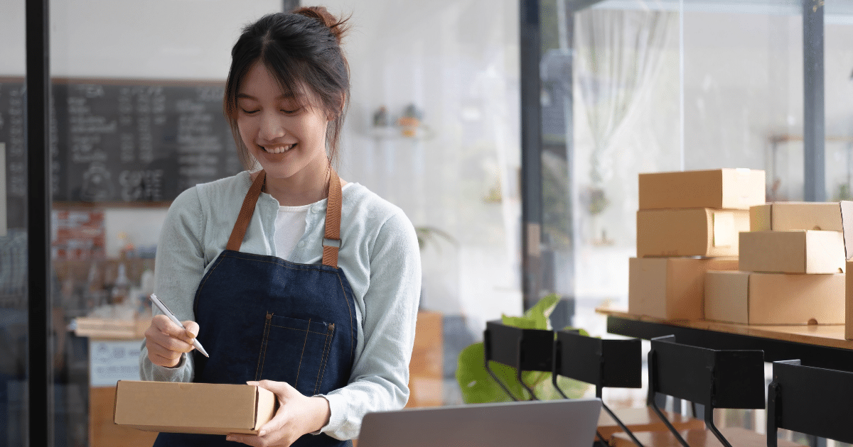 Smiling woman in an apron managing inventory in a small business, highlighting franchise opportunities and entrepreneurship.
