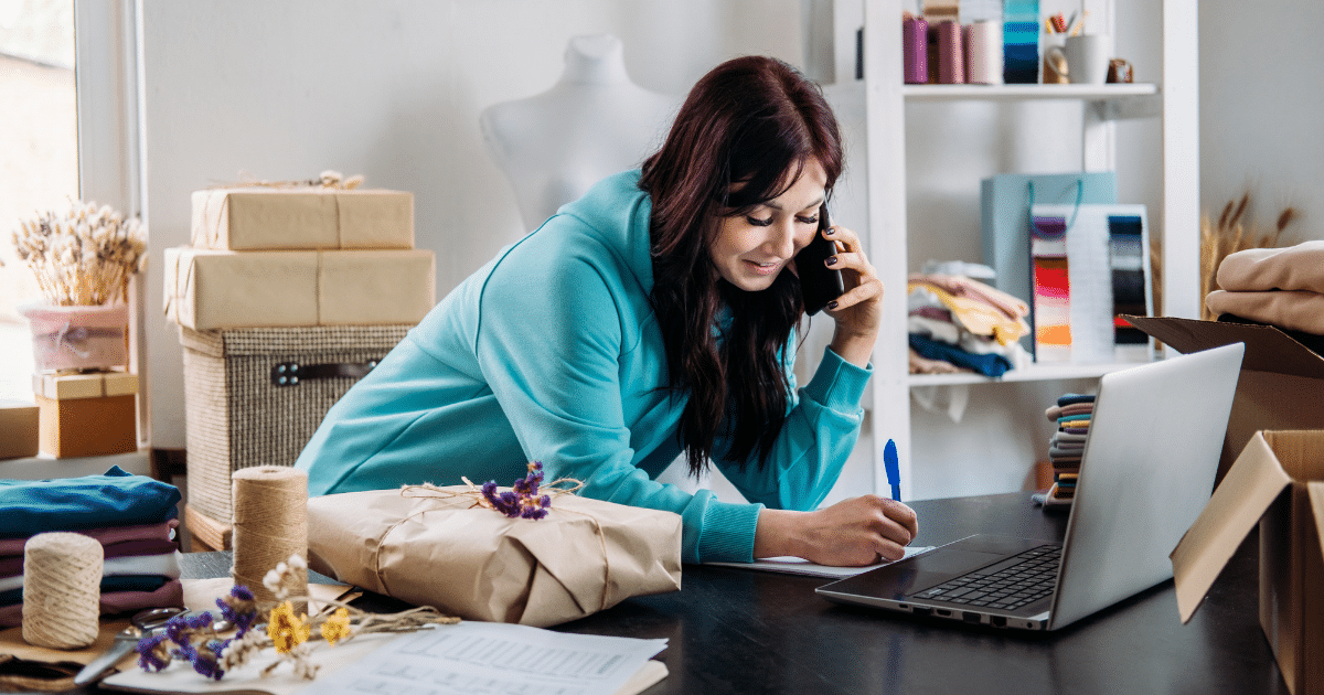 Small business owner managing finances and health care under Obamacare, surrounded by supplies and a laptop.