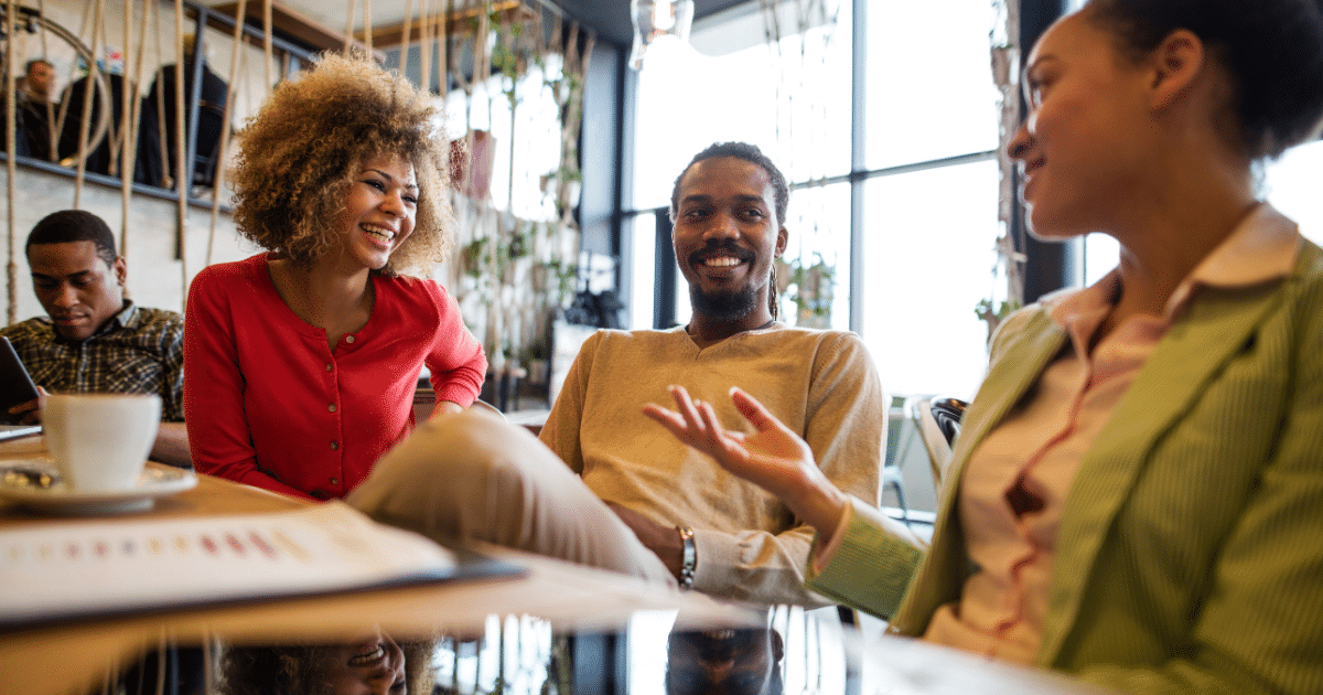 Group of diverse professionals engaging in a friendly discussion over coffee, emphasizing customer loyalty and relationships.