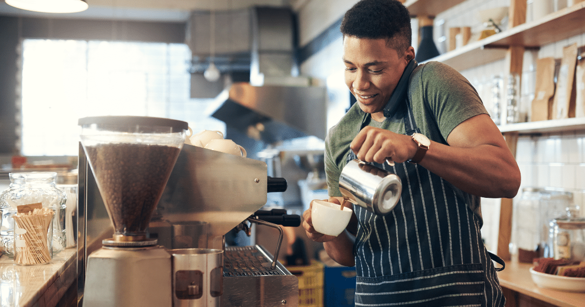 Barista pouring coffee in a cafe, highlighting small business operations in the food and beverage industry.