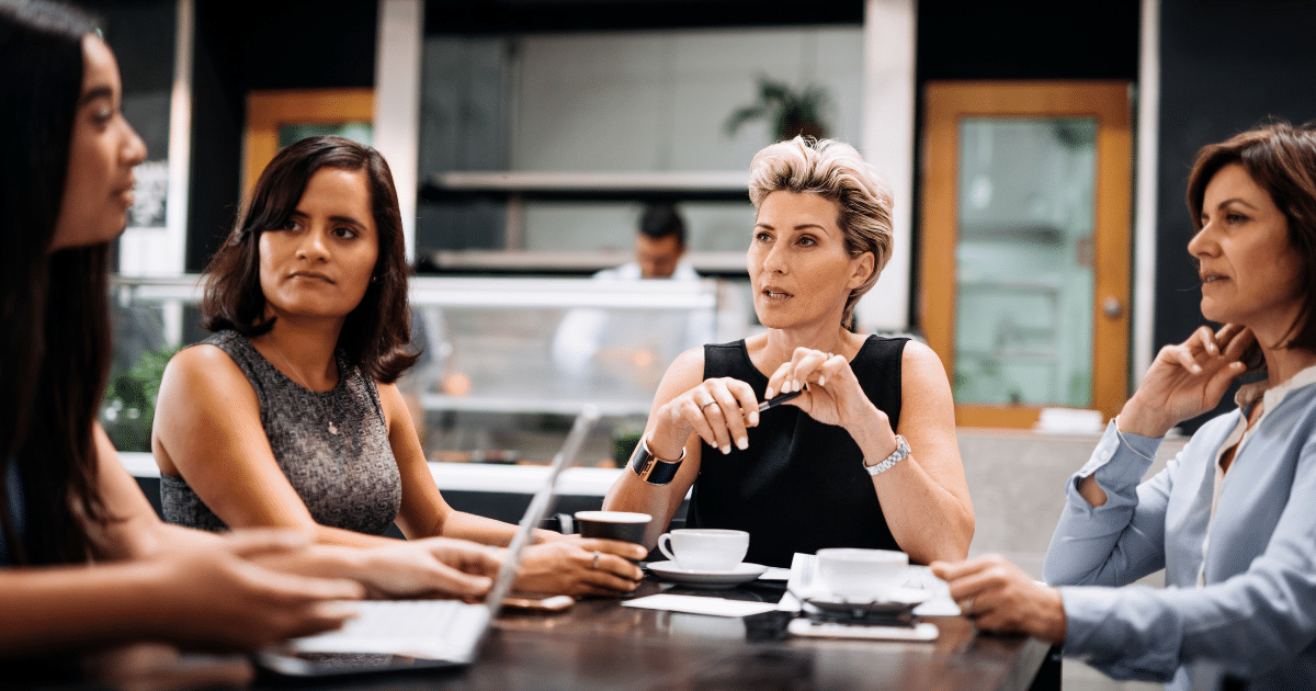 Women discussing smart investing strategies over coffee in a modern workspace, highlighting collaboration and finance.