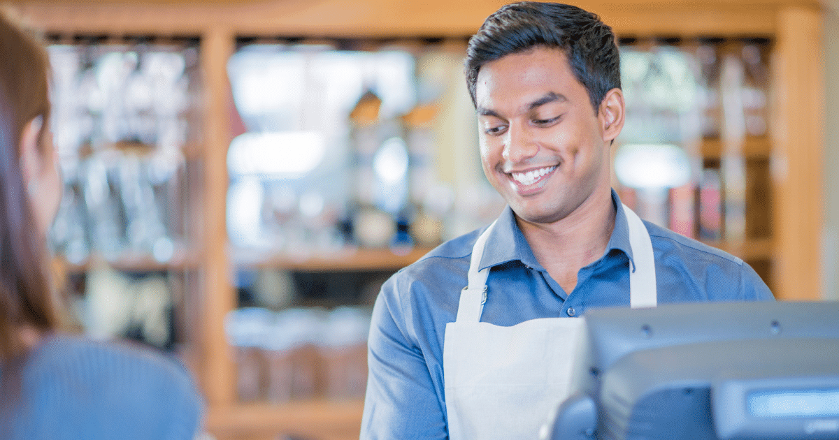 Smiling barista assisting a customer, representing small business growth and financing solutions.