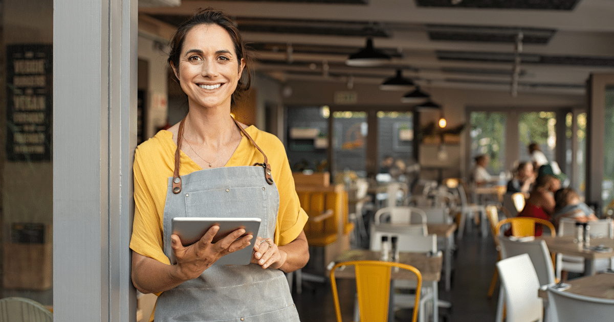Smiling small business owner in a cafe, showcasing summer strategies for success and employee appreciation.