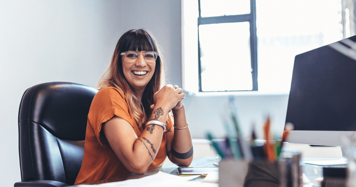 Smiling woman in an office discussing self-employment tax impacts on LLC owners and business financing solutions.
