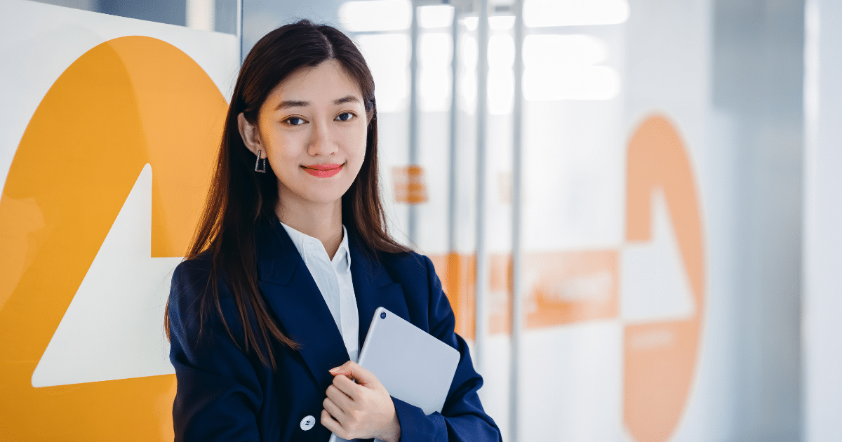 Professional woman in business attire holding a tablet, representing small business owners and the importance of taking vacations.