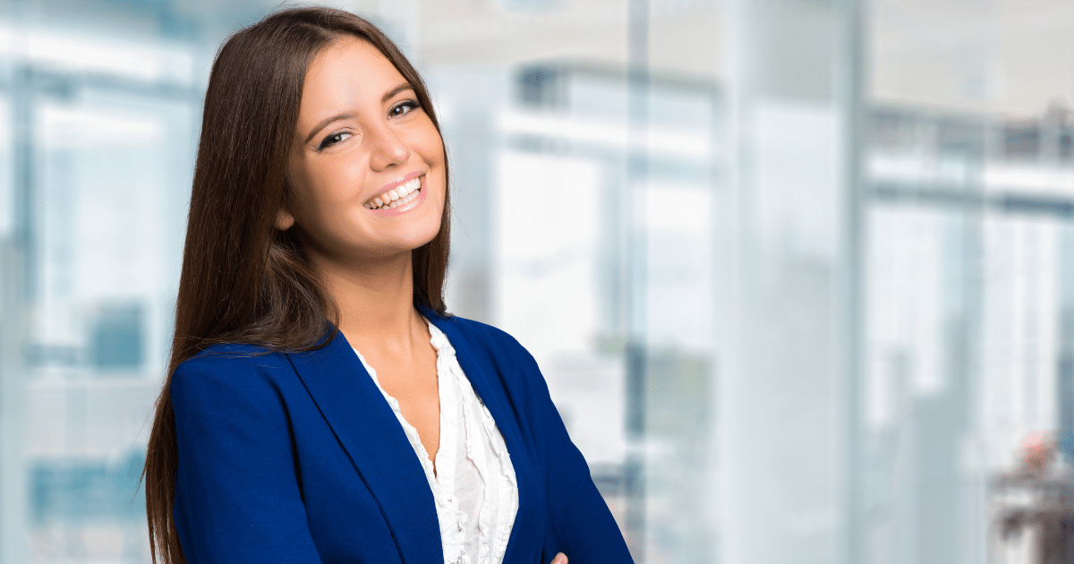 Smiling businesswoman in a blue blazer, representing growth through invoice factoring and loans for companies.