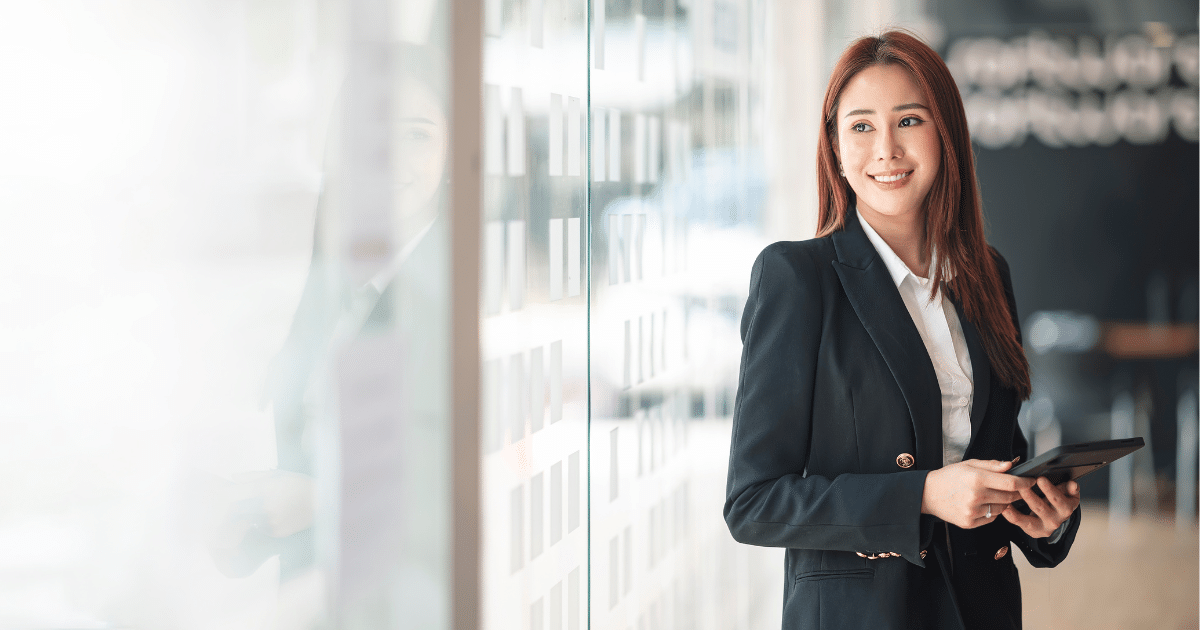 Business professional smiling while holding a tablet, representing success and planning for business growth.