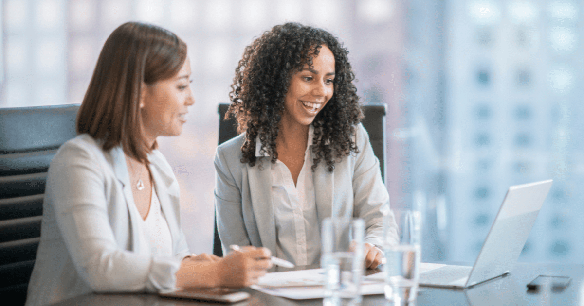 Two businesswomen discussing financing options for small business loans and credit lines in a modern office setting.