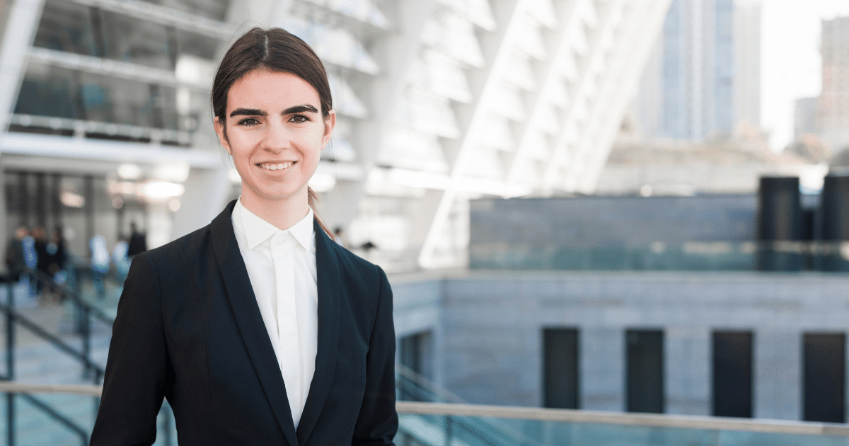 Professional woman in business attire smiling outdoors, representing small business savings strategies and financial empowerment.