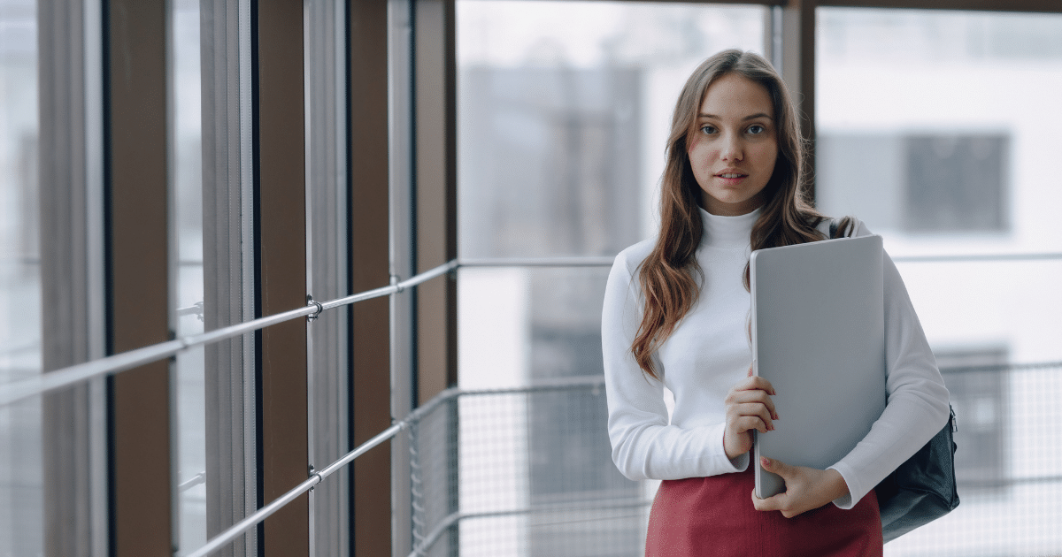 Business professional holding a laptop in a modern office, highlighting mobile technology's impact on business research.
