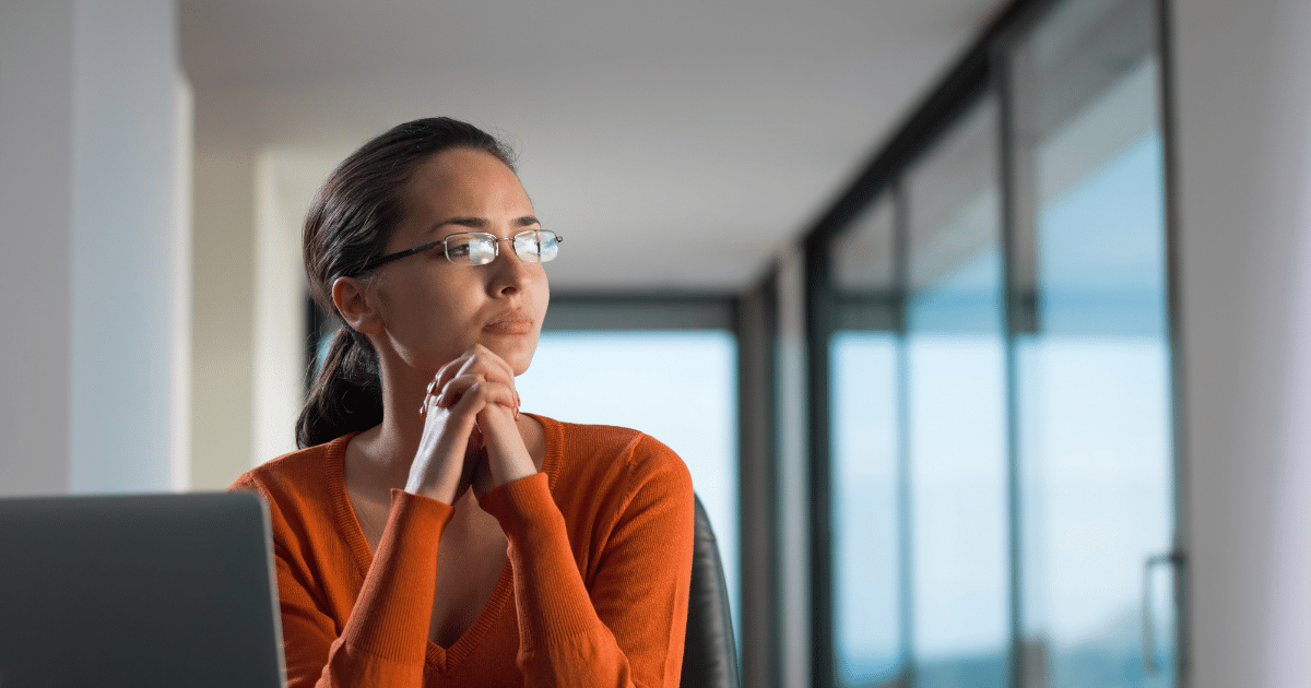 Woman contemplating customer service strategies in a modern office setting, emphasizing over-the-top service excellence.