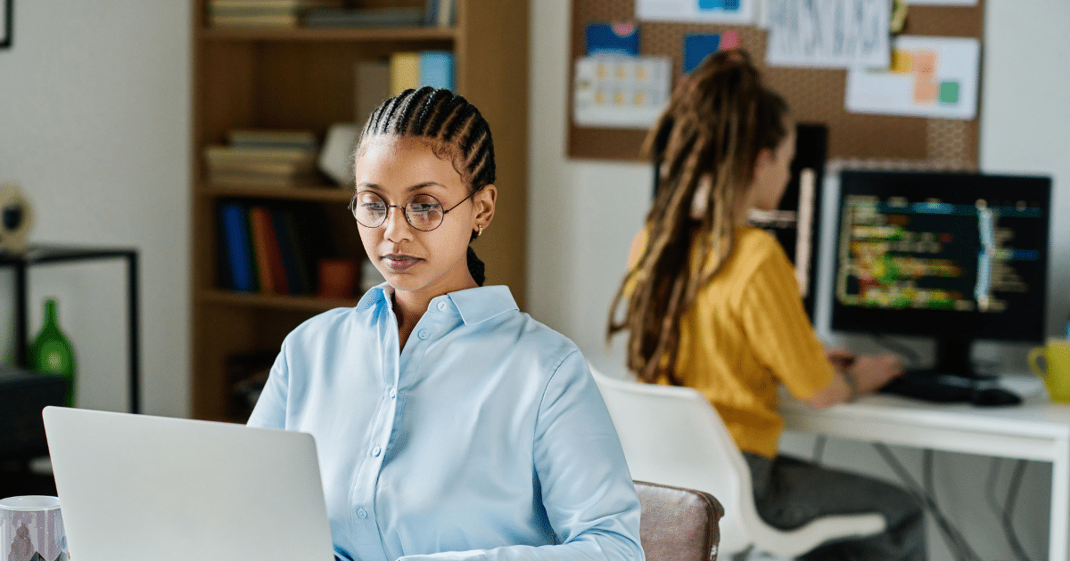 Woman working on a laptop in a modern office, focusing on overcoming public speaking fear and building confidence.