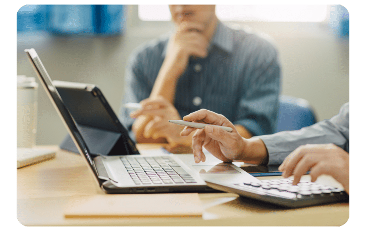Business professionals discussing financing options with a laptop and calculator, focusing on small business loans.