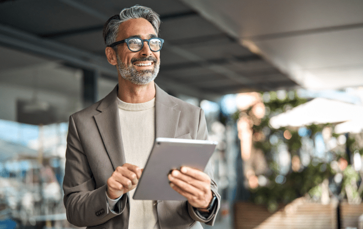 Smiling professional man using a tablet, representing employee empowerment and business growth strategies.