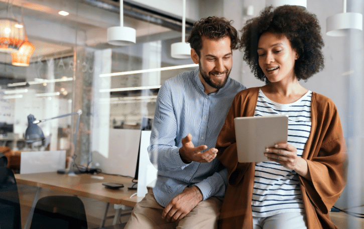 Business professionals discussing financial strategies while reviewing a tablet in a modern office setting.
