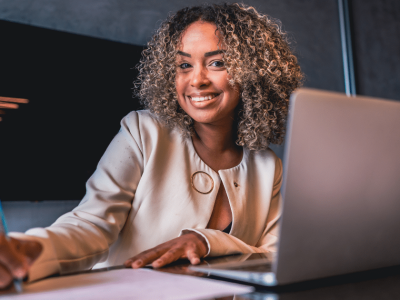 Smiling businesswoman working on a laptop, representing effective expense reduction strategies for small businesses.