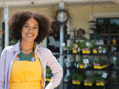 Smiling business owner in an apron outside a plant shop, representing bad credit loans for small business growth.