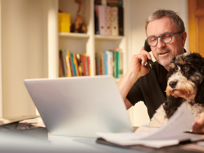 Man on phone with dog, working on real estate investment strategies using unsecured business loans for growth.