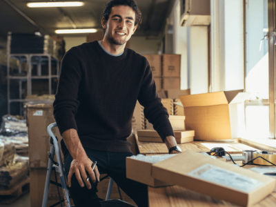 Smiling young man in a warehouse, showcasing equipment leasing and finance solutions for construction businesses.