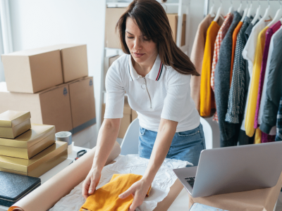Woman packing clothing for an online business, showcasing equipment leasing and financing for growth opportunities.