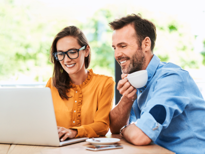 Couple discussing flexible credit options for automotive business financing while using a laptop in a cafe.