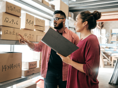 Two business professionals discussing inventory management in a warehouse, highlighting franchise growth and funding opportunities.