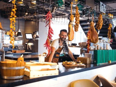 Small business owner in a modern restaurant, showcasing food and decor, highlighting financing options for growth.