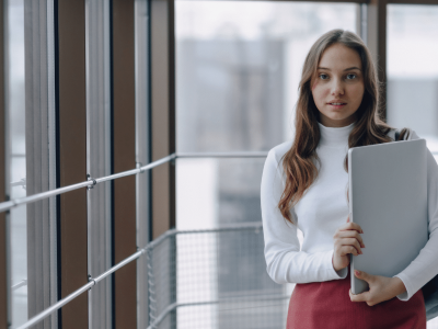 Business professional holding a laptop in a modern office, highlighting mobile technology's impact on business research.