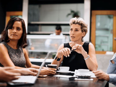 Women discussing smart investing strategies over coffee in a modern workspace, highlighting collaboration and finance.