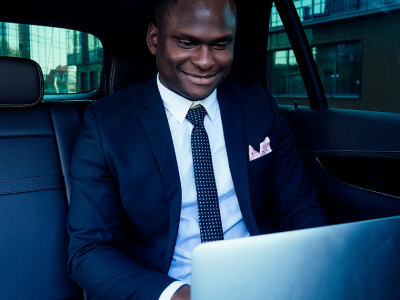 Business professional working on a laptop in a car, highlighting the importance of financial awareness and banking fees.