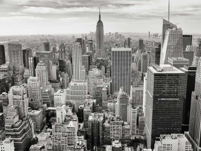 Black and white aerial view of New York City skyline featuring iconic skyscrapers and the Empire State Building.