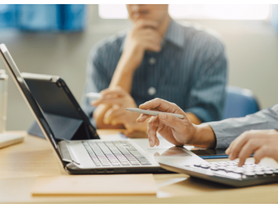 Business professionals discussing financing options with a laptop and calculator, focusing on small business loans.