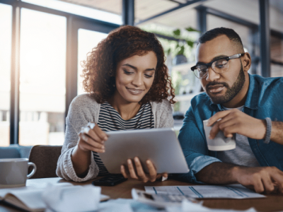 Couple reviewing financial information on a tablet, exploring new credit opportunities and FICO score improvements.
