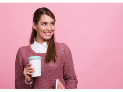 Smiling woman holding a coffee cup and notebook, representing small business empowerment and financing solutions.