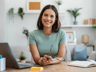 Smiling woman at a desk with a laptop, representing business financing and line of credit solutions.
